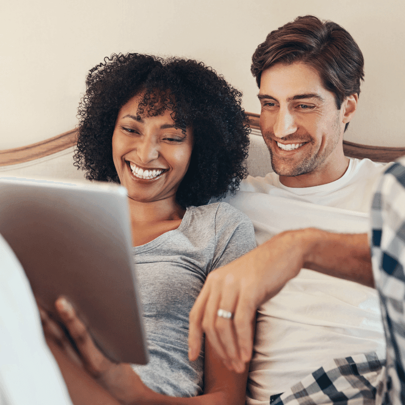 Happy couple looking at tablet together during online therapy session