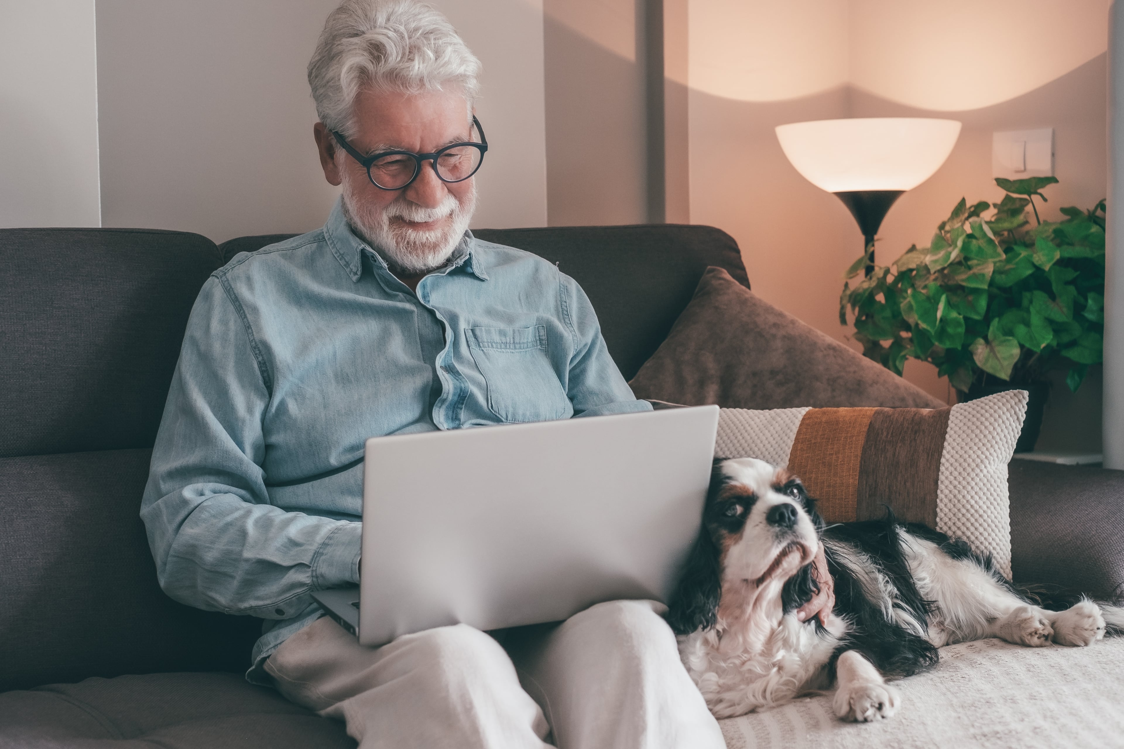 Senior man participating in online therapy from the comfort of his home with his dog