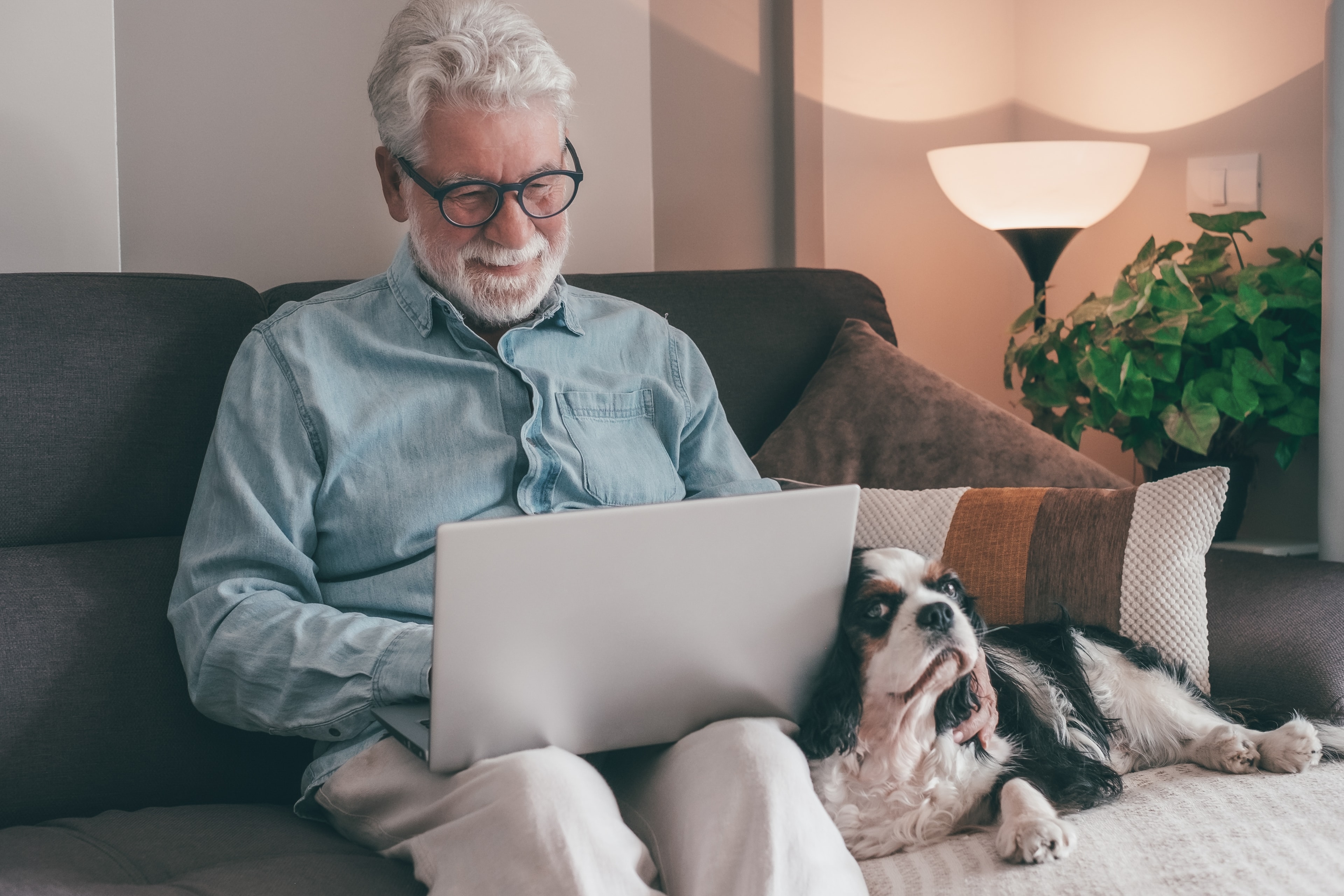 Senior man participating in online therapy from the comfort of his home with his dog