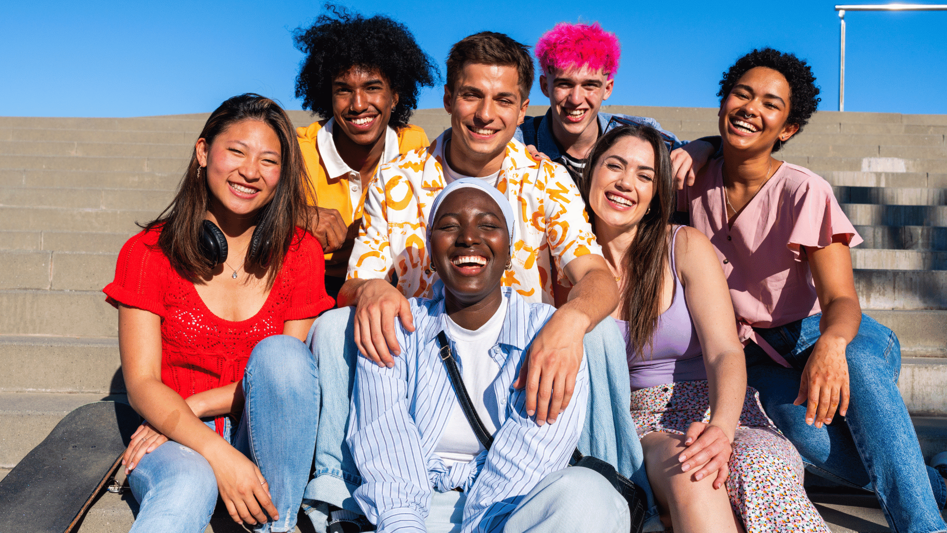 Diverse group of young people from different cultural backgrounds smiling together, representing inclusivity and community support