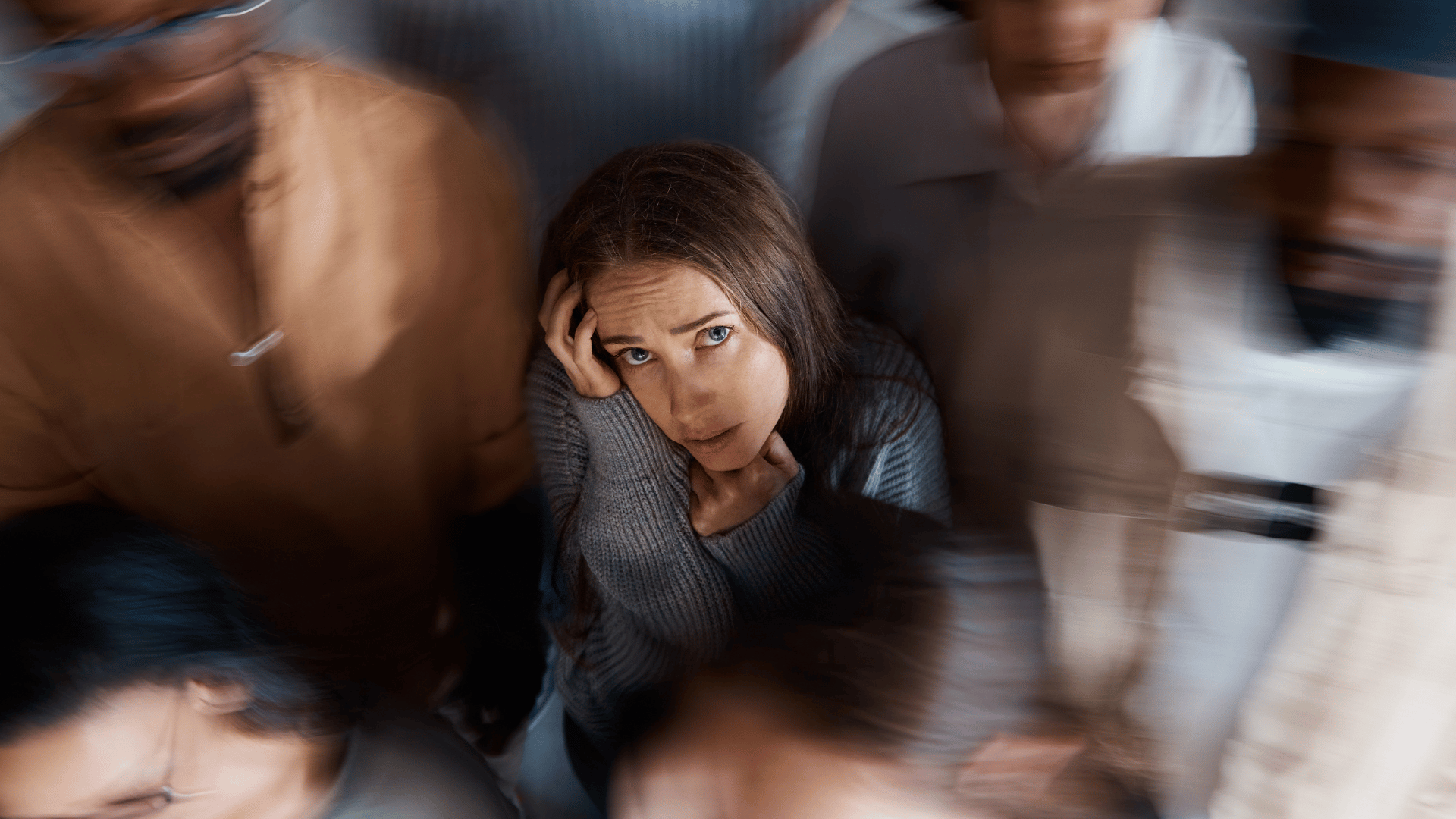 Person experiencing anxiety surrounded by blurred figures, representing panic disorder symptoms