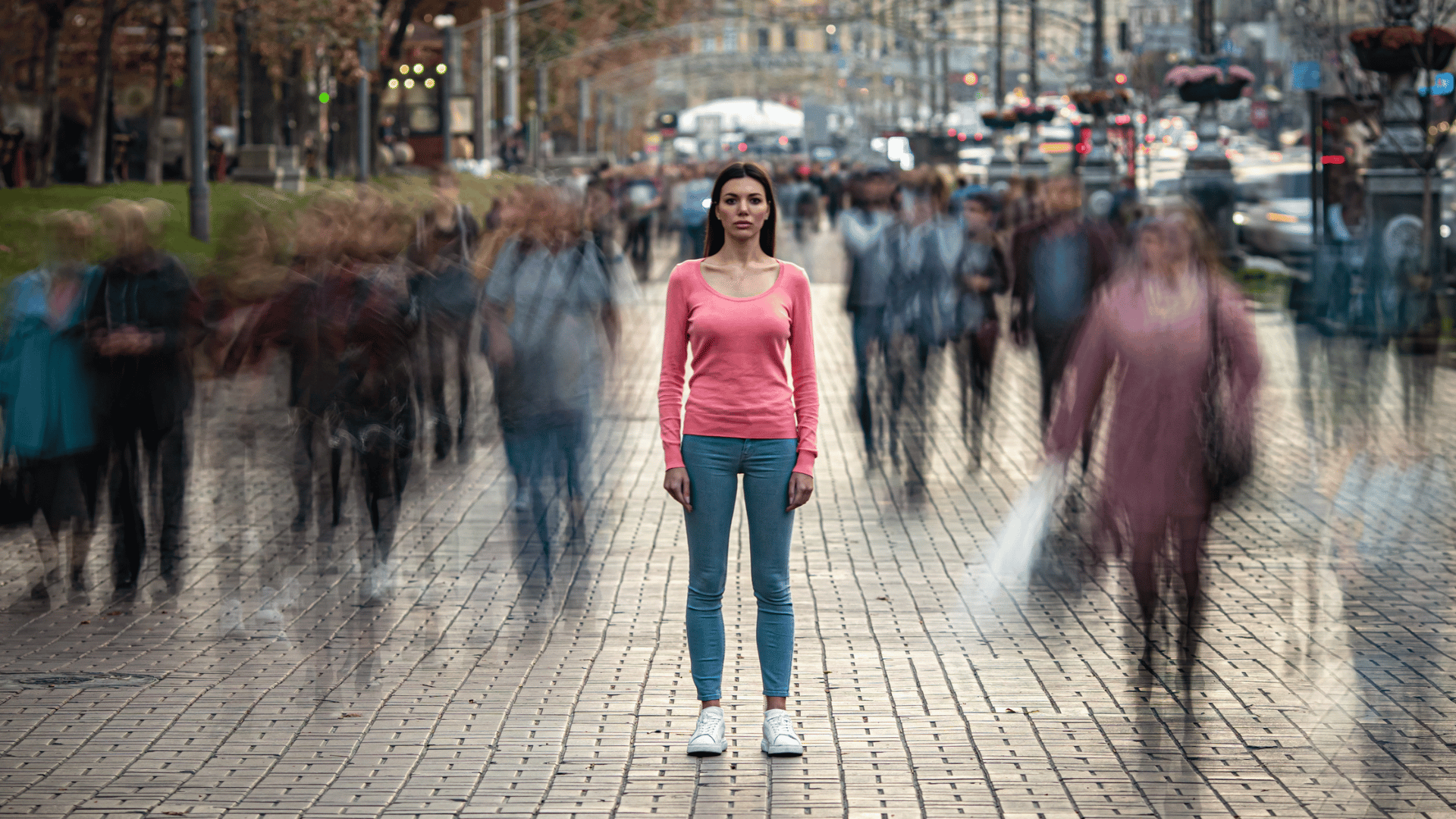 Person standing still amidst a busy city street, representing the experience of feeling disconnected