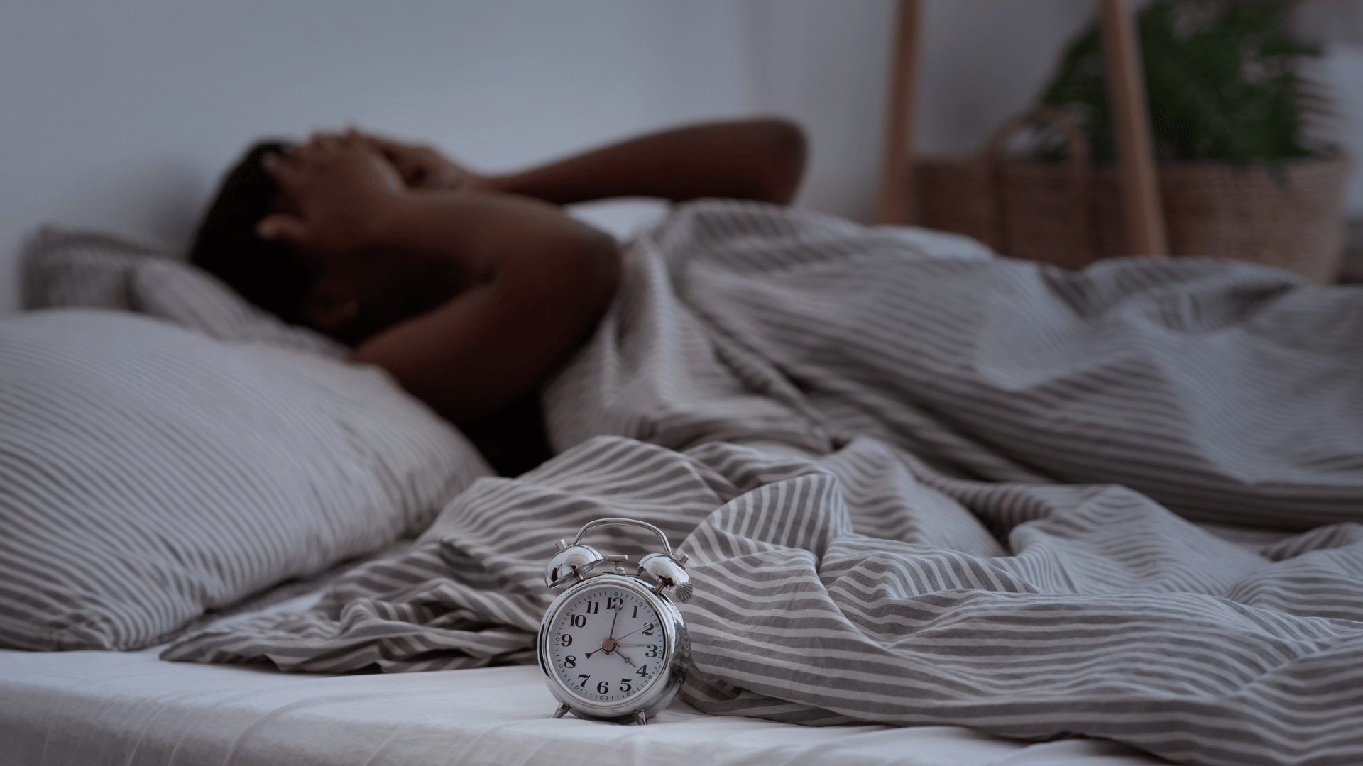 Person experiencing sleep difficulties with an alarm clock showing early morning hours